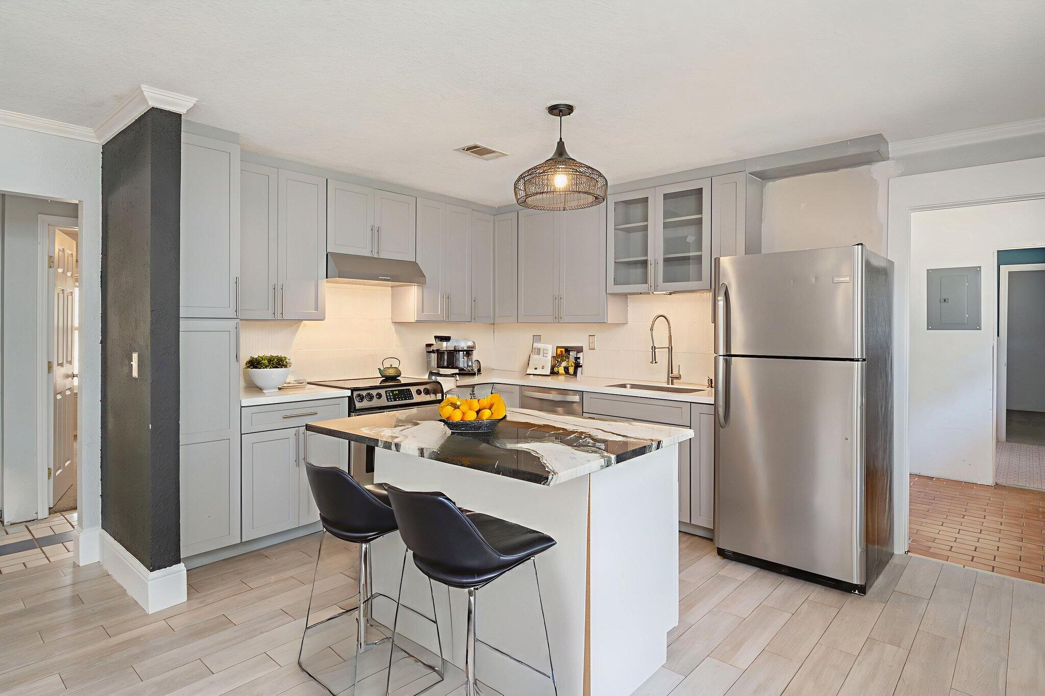 a kitchen with stainless steel appliances granite countertop a refrigerator a sink dishwasher a stove and white cabinets with wooden floor