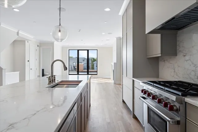 a kitchen with stainless steel appliances a sink stove and wooden floor
