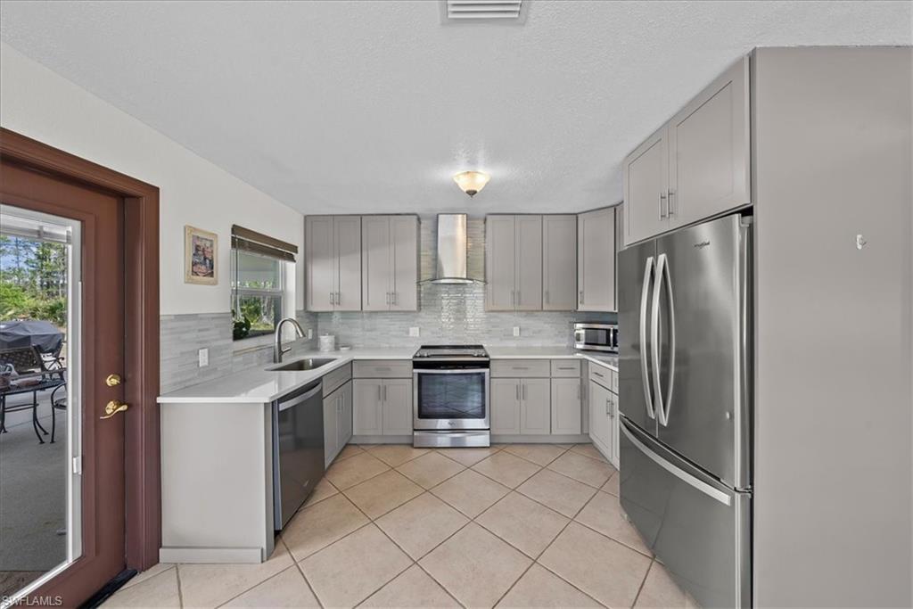 6070 Lee Williams Road Naples, FL 34117 - Photo 11 of 26 a kitchen with stainless steel appliances granite countertop a refrigerator sink and stove