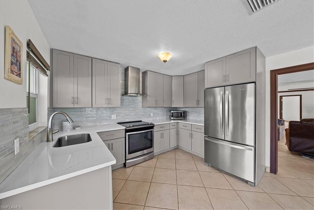 6070 Lee Williams Road Naples, FL 34117 - Photo 13 of 26 a kitchen with stainless steel appliances granite countertop a refrigerator sink and stove