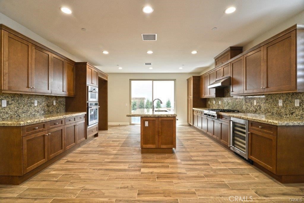 128 Brambles Irvine, CA 92618 - Photo 4 of 27 a large kitchen with kitchen island granite countertop a stove top oven a sink dishwasher a dining table and chairs with wooden floor