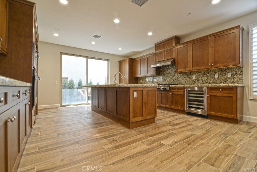 128 Brambles Irvine, CA 92618 - Photo 6 of 27 a kitchen with stainless steel appliances granite countertop a stove top oven a sink dishwasher and a refrigerator with wooden floor