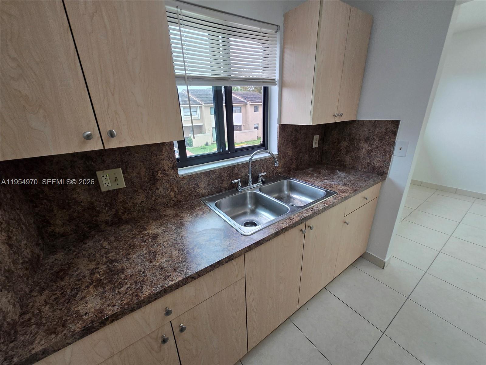 15439 Southwest 80th Street, Unit 2029 Miami, FL 33193 - Photo 8 of 16 a kitchen with granite countertop a sink and a white cabinets