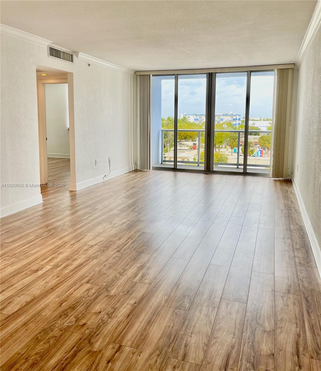 401 69th Street, Unit 405 Miami Beach, FL 33141 - Photo 3 of 25 wooden floor in an empty room with a window