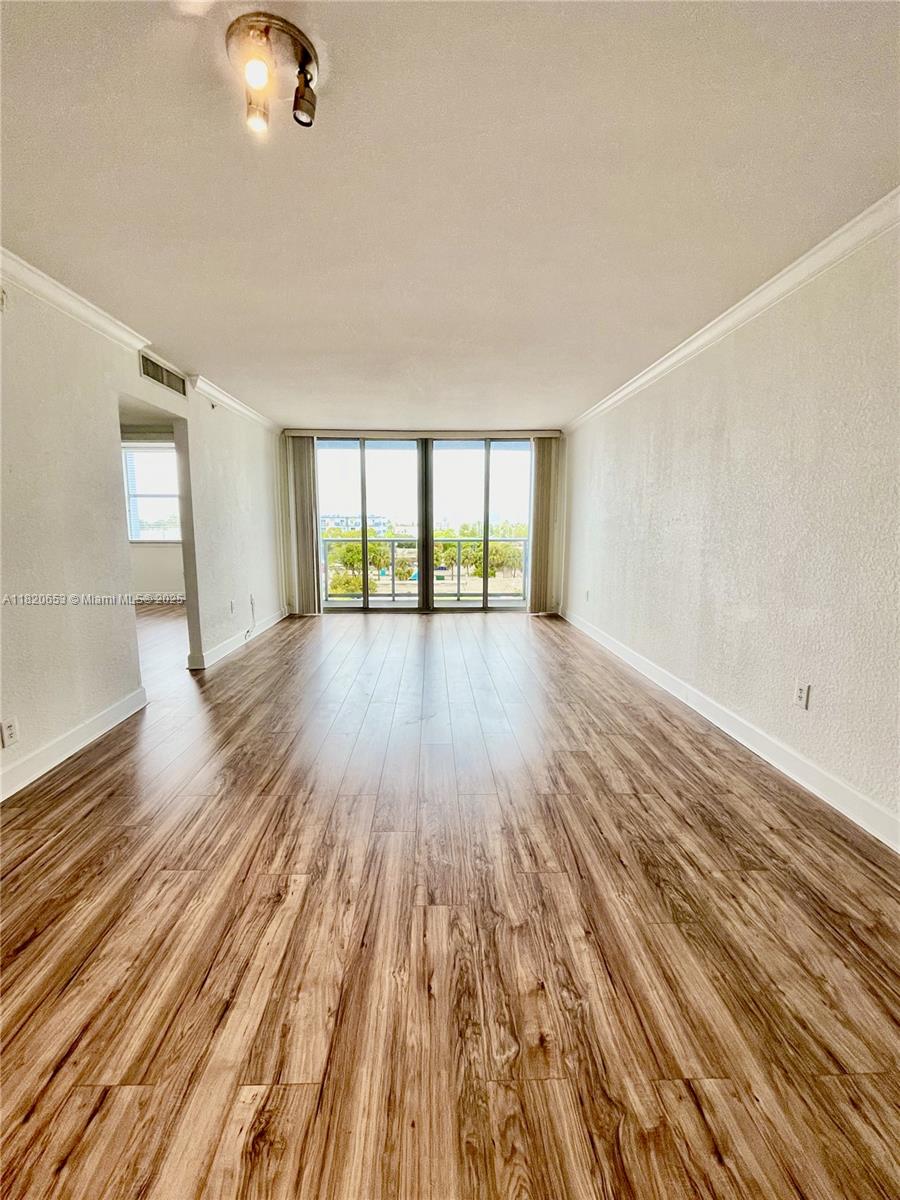 401 69th Street, Unit 405 Miami Beach, FL 33141 - Photo 6 of 25 an empty room with wooden floor and windows