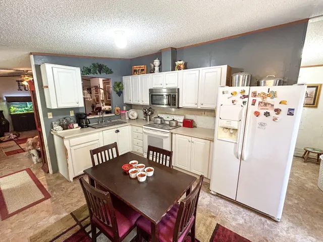 a kitchen with a refrigerator a stove a sink dishwasher a dining table and chairs