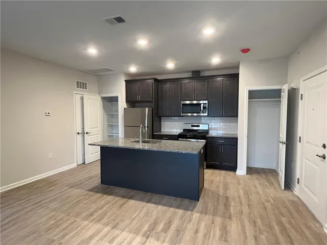 a kitchen with stainless steel appliances granite countertop a refrigerator and a wooden floors