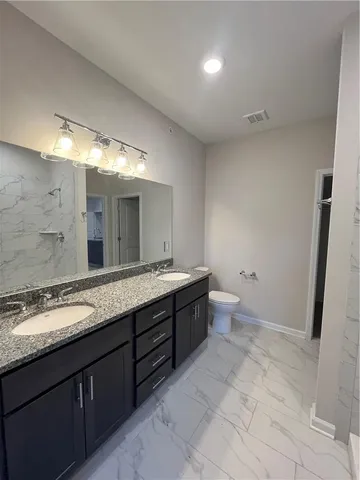 a spacious bathroom with a granite countertop sink mirror and a toilet
