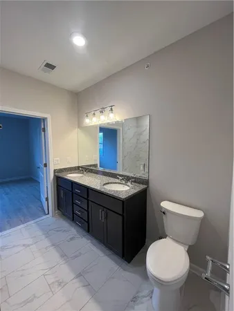 a bathroom with a granite countertop toilet sink and mirror