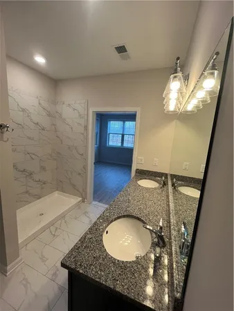 a bathroom with a granite countertop sink a toilet and shower