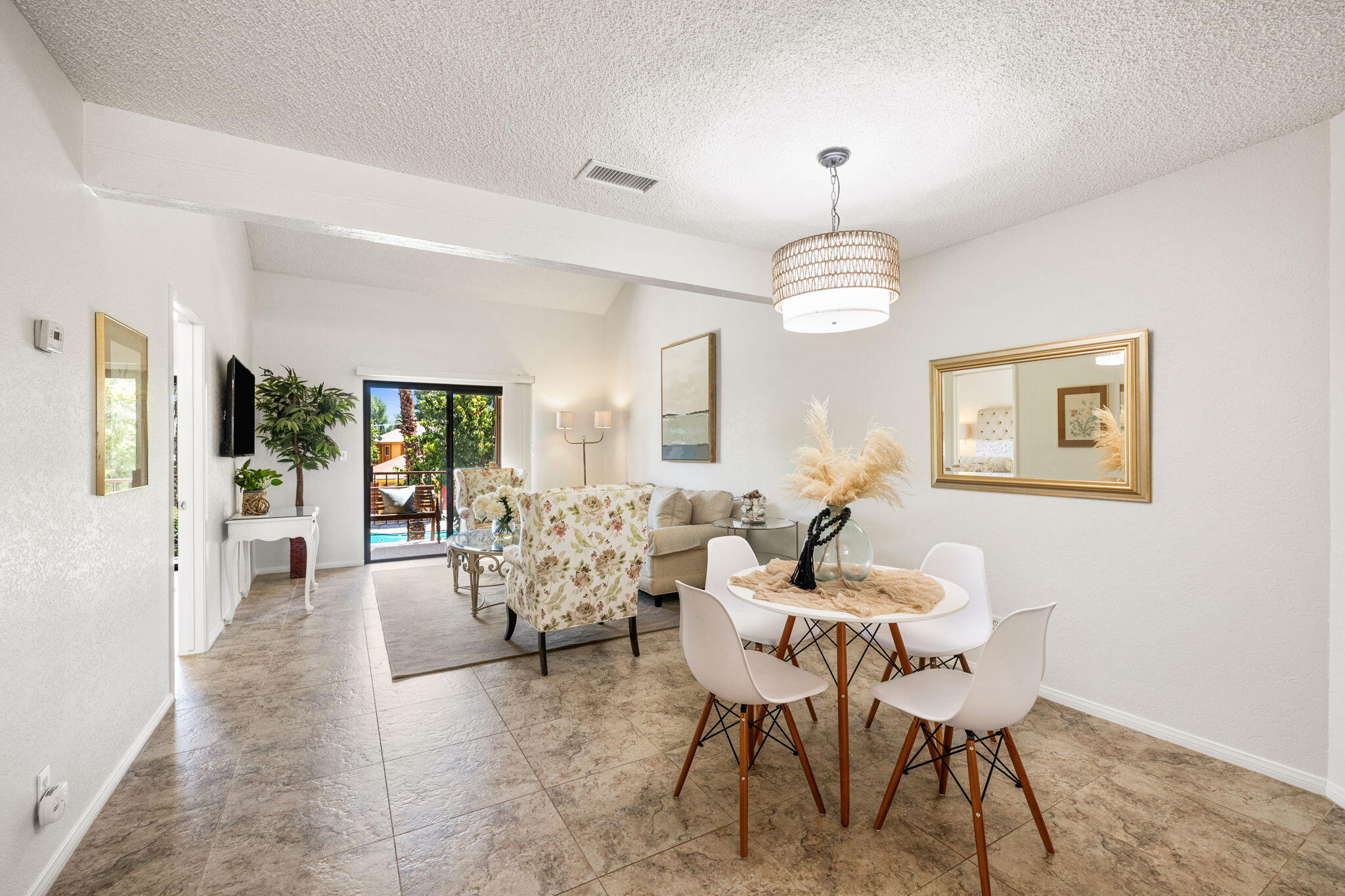 48255 Monroe Street, Unit 59 Indio, CA 92201 - Photo 8 of 58 a dining room with wooden floor a chandelier a glass table and chairs