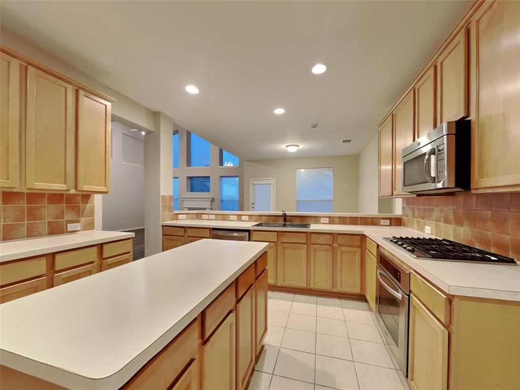 4808 Winterview Drive Mansfield, TX 76063 - Photo 4 of 32 Kitchen featuring light tile patterned flooring, light countertops, a peninsula, appliances with stainless steel finishes, and a sink