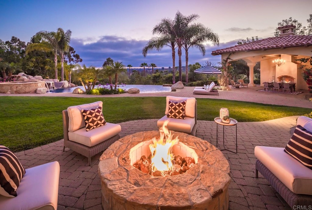6971 Rancho La Cima Drive Rancho Santa Fe, CA 92067 - Photo 1 of 1 a view of a swimming pool and lounge chairs in back of the house