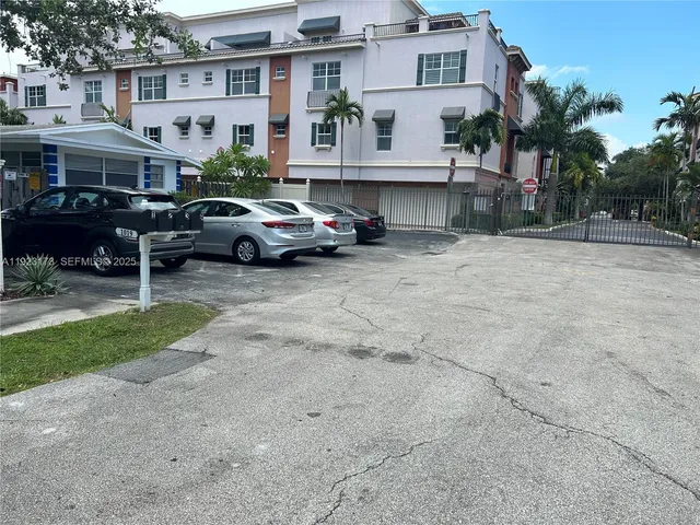 a front view of a building with a garden and car parked