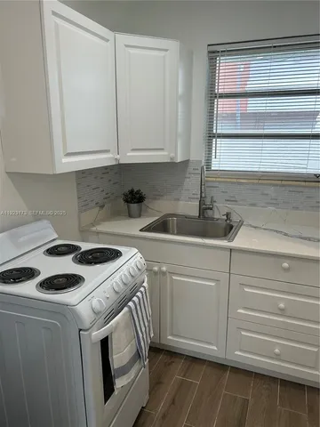 a kitchen with white cabinets and sink
