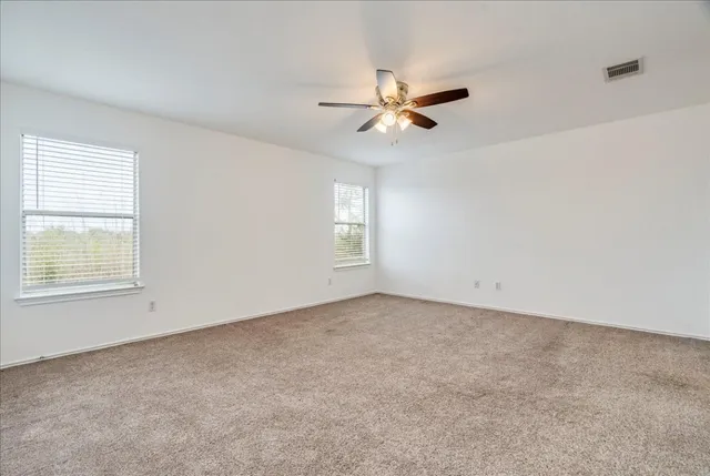 an empty room with a window and a fan