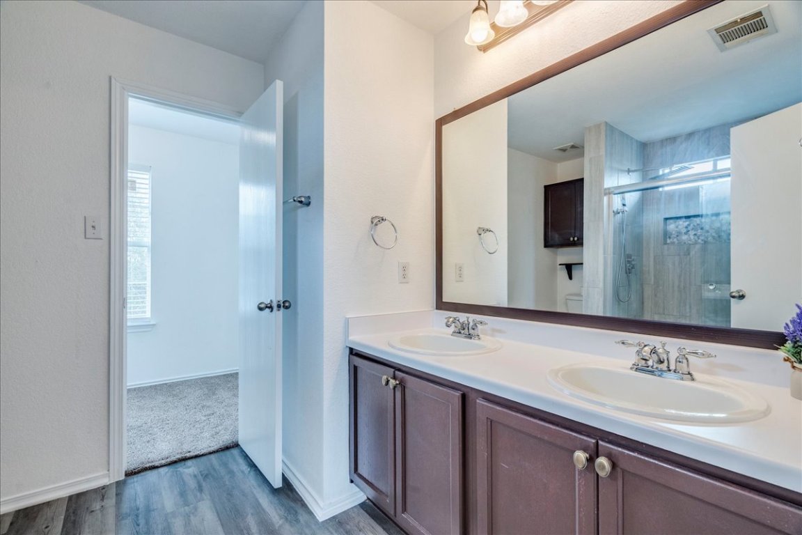 18436 Wind Tree Lane Elgin, TX 78621 - Photo 17 of 34 Full bathroom with double vanity, large mirror, plenty of cabinet storage and dark wood-style floors
