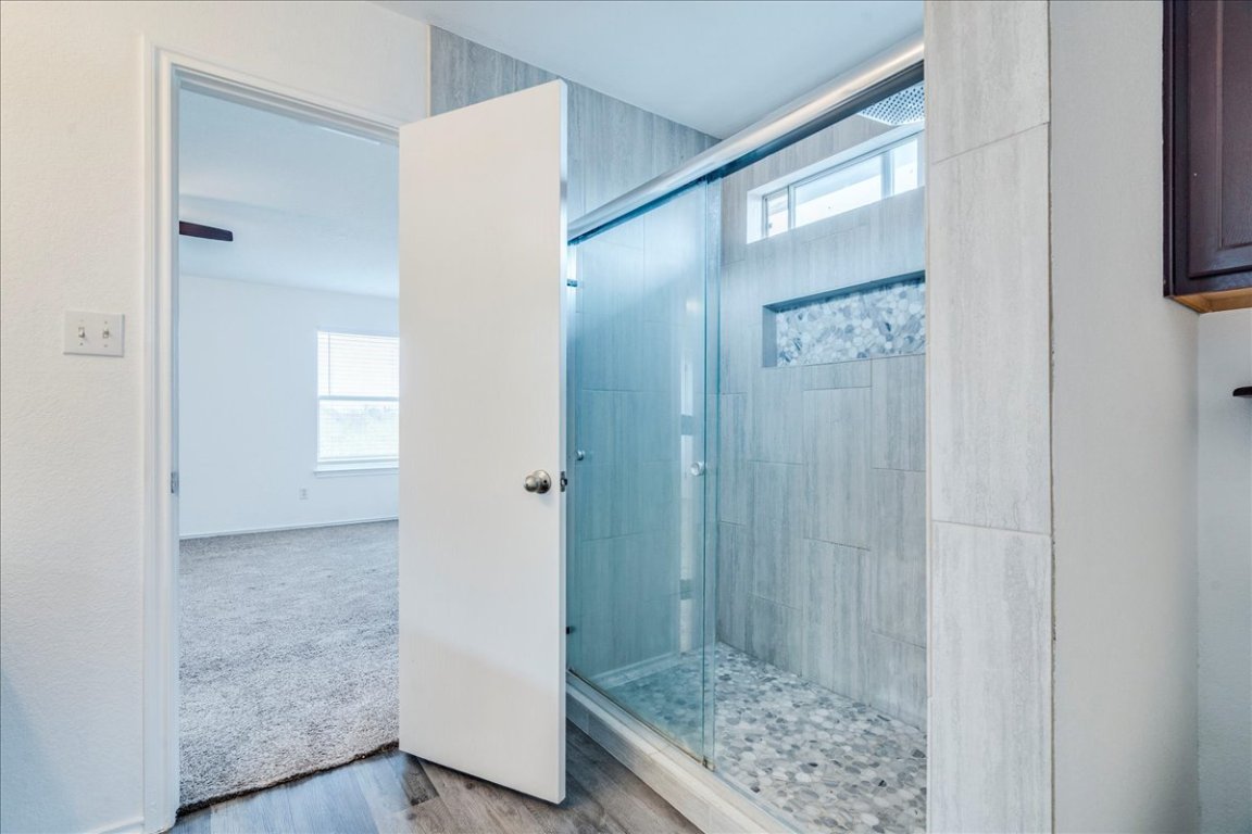 18436 Wind Tree Lane Elgin, TX 78621 - Photo 18 of 34 Bathroom featuring plenty of natural light, bright tiled shower, and wood finished floors