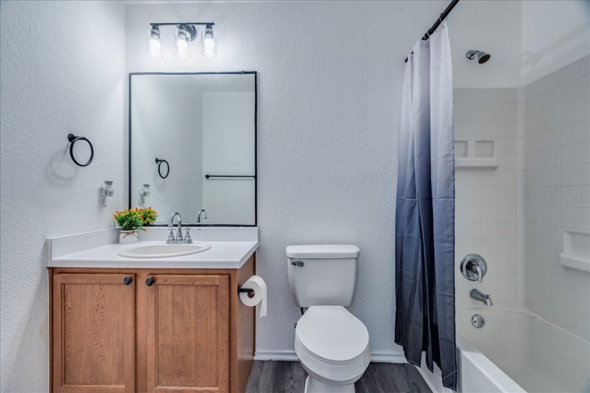18436 Wind Tree Lane Elgin, TX 78621 - Photo 24 of 34 a bathroom with a granite countertop toilet a sink and a mirror