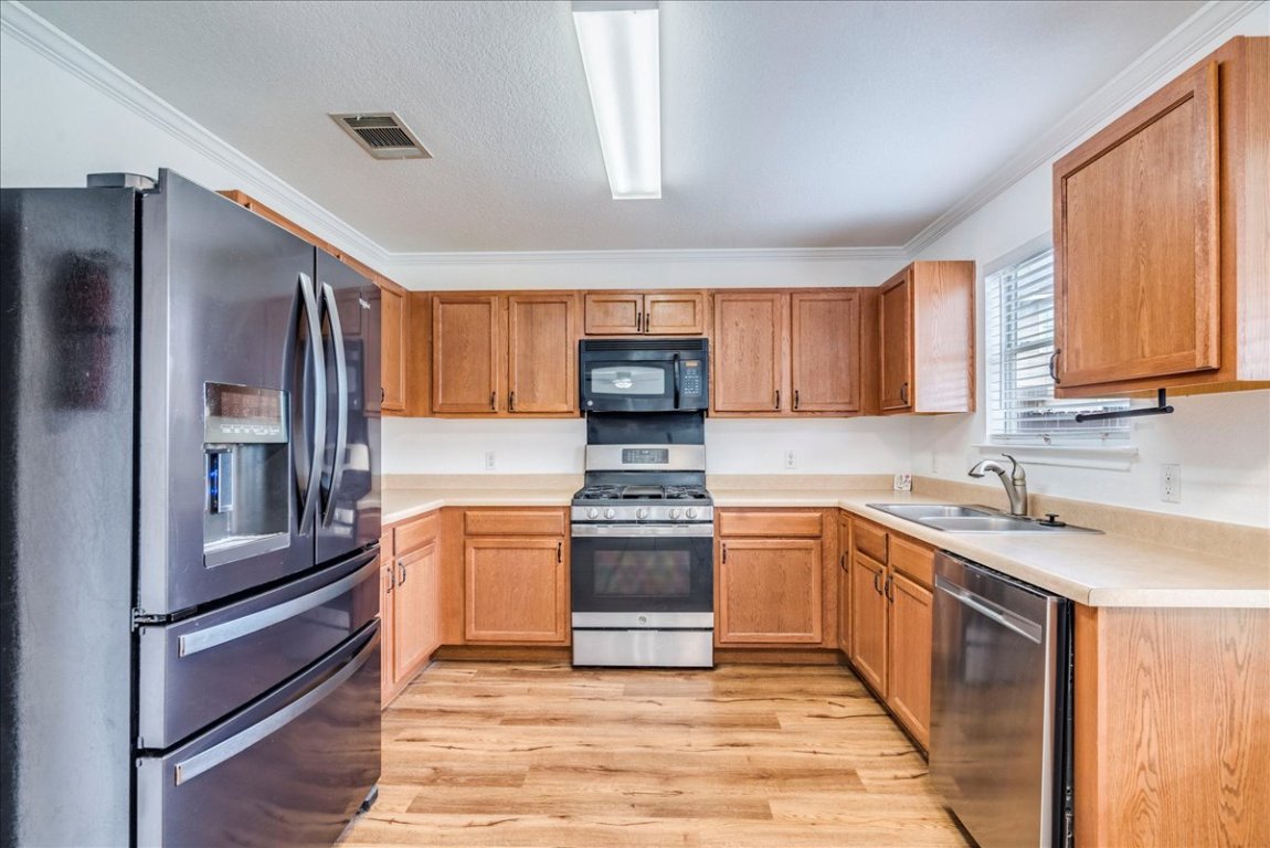 18436 Wind Tree Lane Elgin, TX 78621 - Photo 7 of 34 a kitchen with stainless steel appliances granite countertop a refrigerator sink and stove