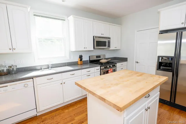 a kitchen with stainless steel appliances white cabinets and wooden floor