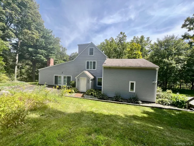 a view of a house with a yard and a large tree