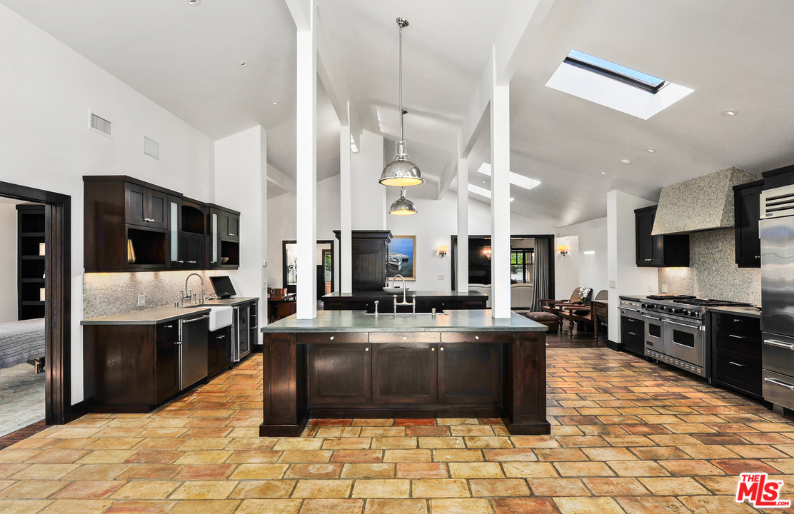 6172 Bonsall Drive Malibu, CA 90265 - Photo 20 of 40 a large kitchen with stainless steel appliances kitchen island granite countertop a large stove a sink a dining table and chairs