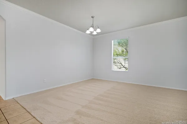 an empty room with chandelier fan and windows