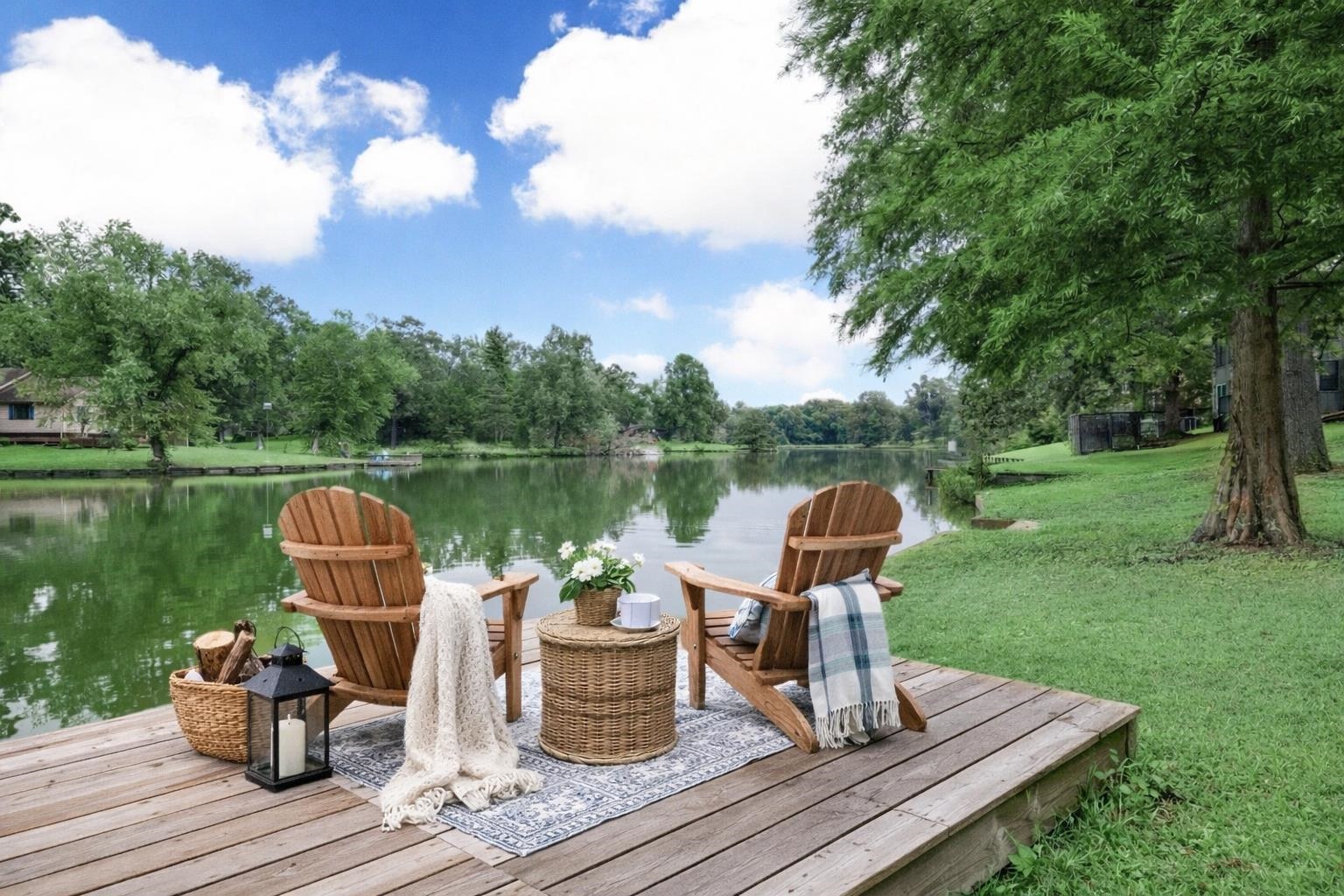 a view of a lake with table and chairs and potted plants with wooden floor and fence