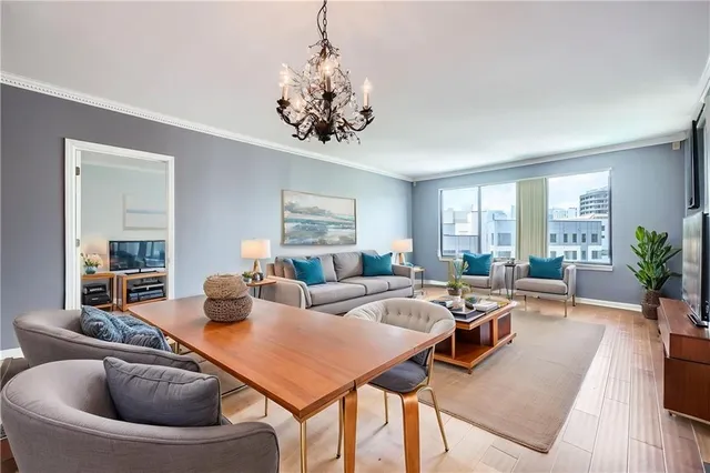 a living room with furniture a chandelier and a wooden floor