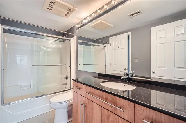 a bathroom with a granite countertop sink mirror toilet and bathtub