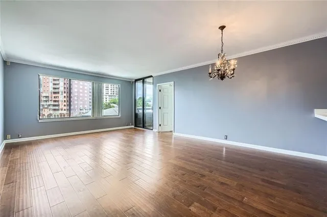 a view of an empty room with window and wooden floor