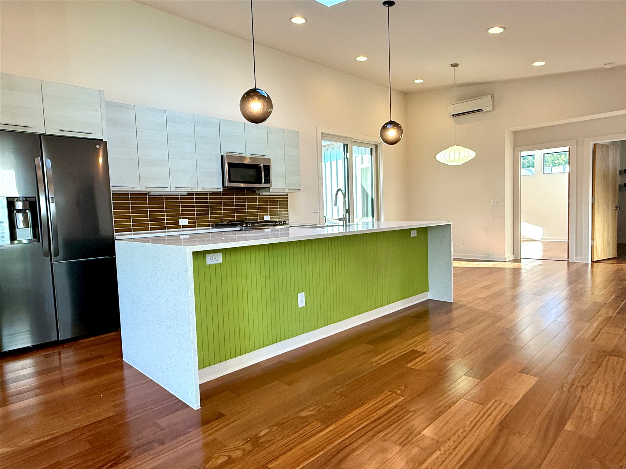 416 Starlight Village Loop Leander, TX 78641 - Photo 10 of 28 Kitchen featuring stainless steel appliances, a center island with sink, decorative backsplash, dark wood finished floors, and decorative light fixtures