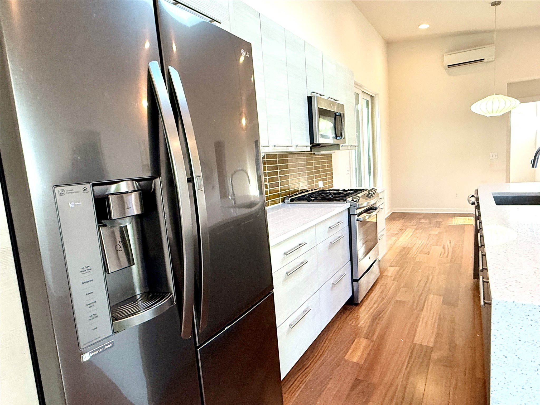 416 Starlight Village Loop Leander, TX 78641 - Photo 12 of 28 Kitchen featuring stainless steel appliances, light wood finished floors, light stone counters, backsplash, and white cabinets