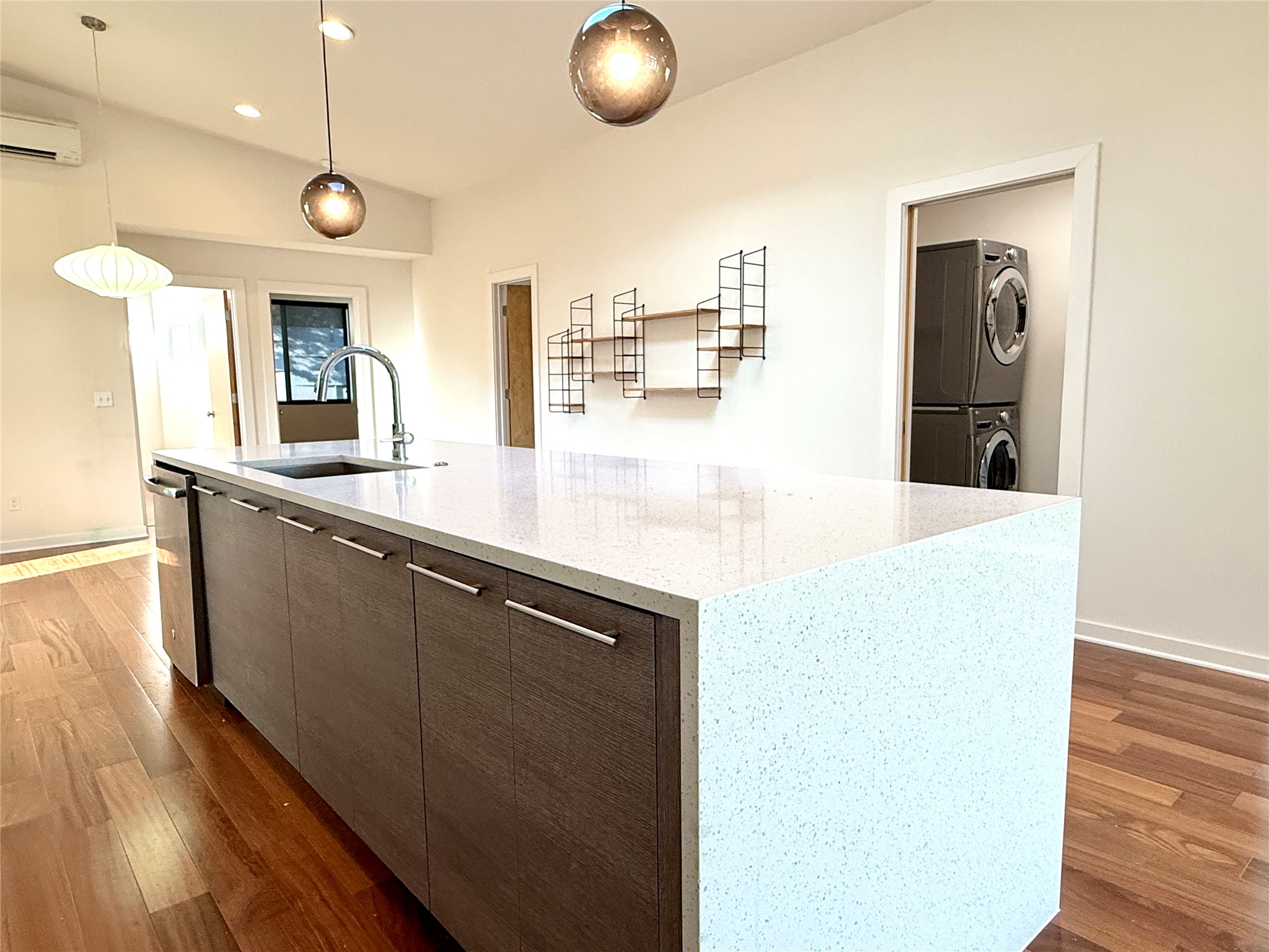 416 Starlight Village Loop Leander, TX 78641 - Photo 15 of 28 Kitchen featuring dark wood-style flooring, a center island with sink, modern cabinets, light stone countertops, and dark wood finish cabinetry