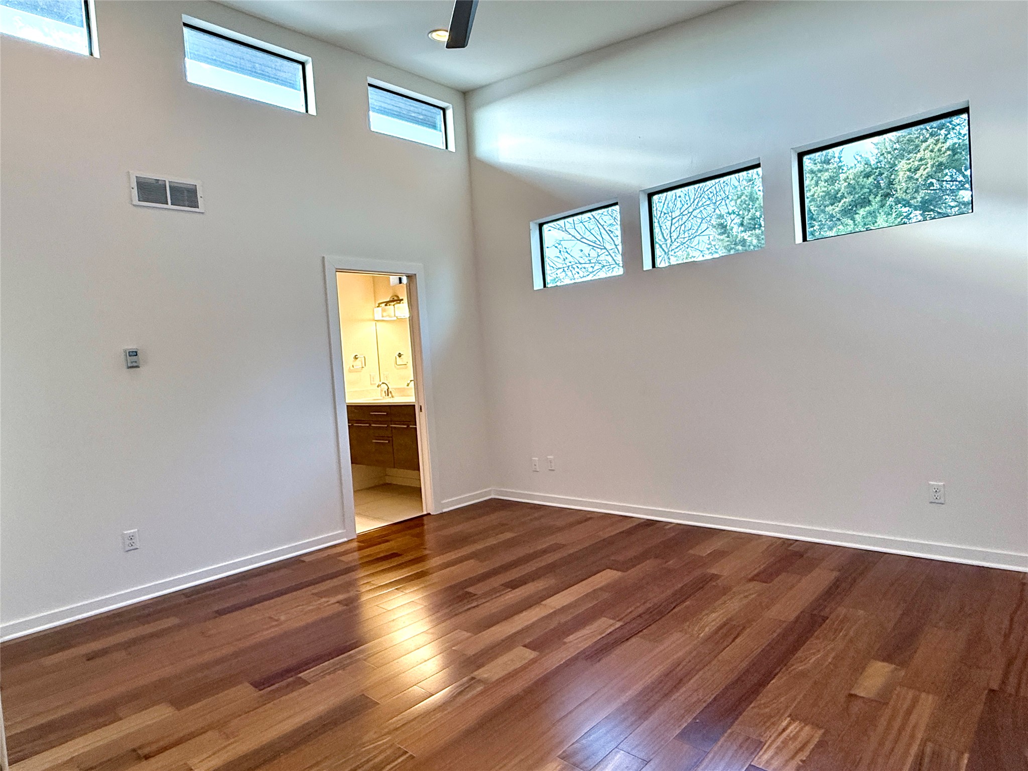 416 Starlight Village Loop Leander, TX 78641 - Photo 19 of 28 Unfurnished bedroom with dark wood finished floors, a high ceiling, a ceiling fan, and ensuite bath