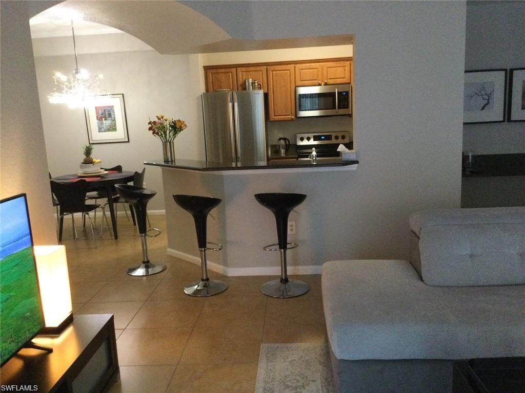 12975 Positano Circle, Unit 202 Naples, FL 34105 - Photo 2 of 14 a living room with furniture and a flat screen tv