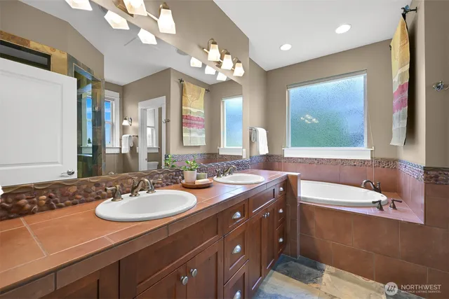 a bathroom with a sink double vanity granite tub and a mirror