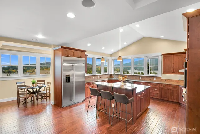 a kitchen with stainless steel appliances granite countertop a table chairs sink and cabinets
