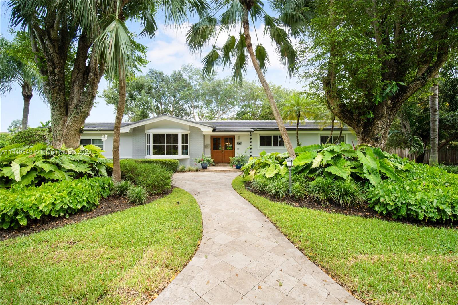 13001 Southwest 70th Avenue Pinecrest, FL 33156 - Photo 1 of 49 a front view of a house with a garden
