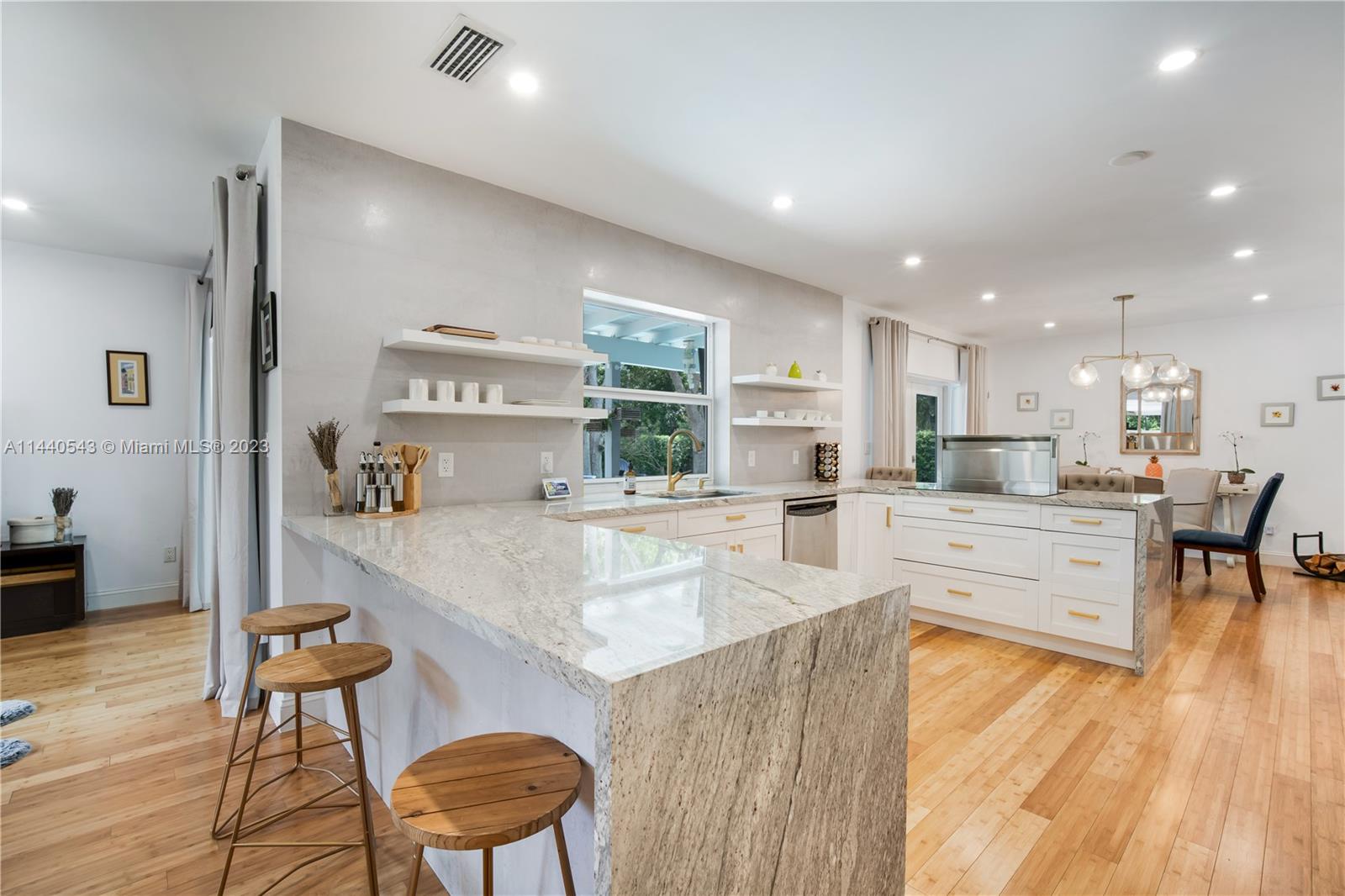 13001 Southwest 70th Avenue Pinecrest, FL 33156 - Photo 18 of 49 a large dining hall with stainless steel appliances granite countertop a stove a sink a dining table and chairs with wooden floor