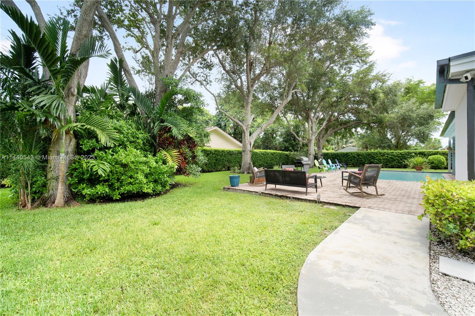 13001 Southwest 70th Avenue Pinecrest, FL 33156 - Photo 42 of 49 a view of a swimming pool with lawn chairs and a big yard