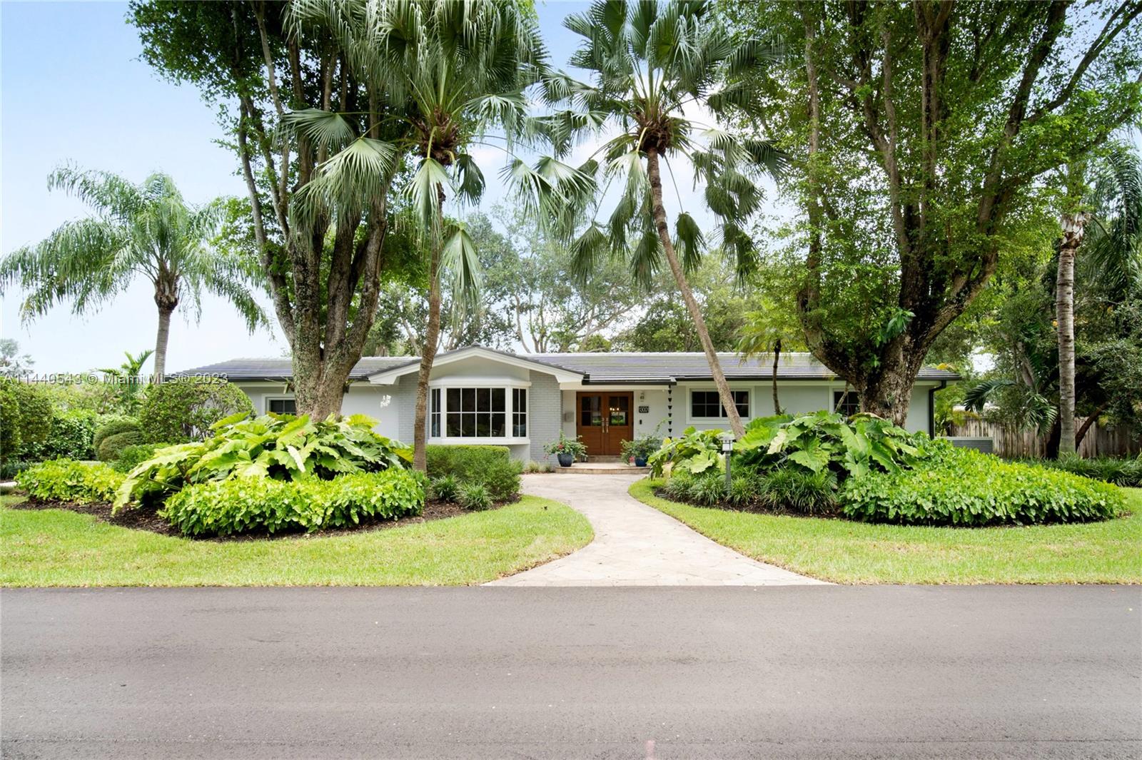 13001 Southwest 70th Avenue Pinecrest, FL 33156 - Photo 5 of 49 a front view of a house with a garden and trees