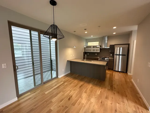 a kitchen with stainless steel appliances kitchen island wooden cabinets granite counter tops and a wooden floor