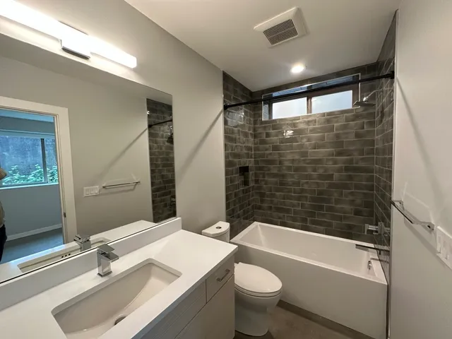 a bathroom with a bathtub shower sink vanity and toilet