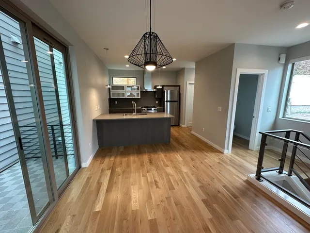 a view of a living room and a kitchen with wooden floor