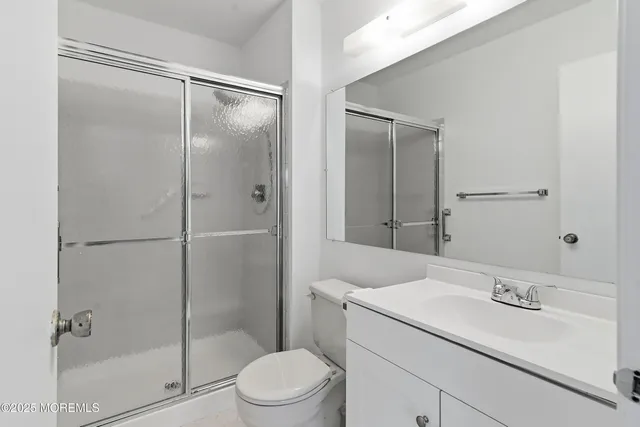a bathroom with a shower sink vanity mirror and toilet