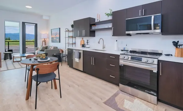 a kitchen with stainless steel appliances stove microwave refrigerator dining table and chairs