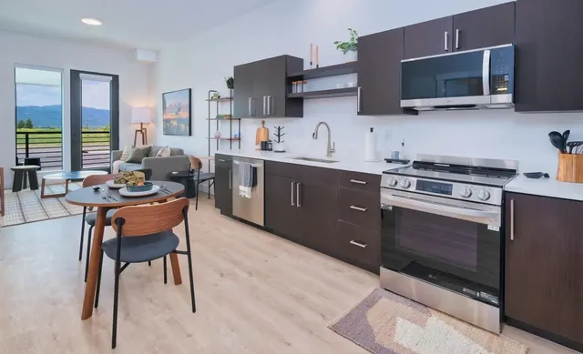 a kitchen with stainless steel appliances stove microwave refrigerator dining table and chairs