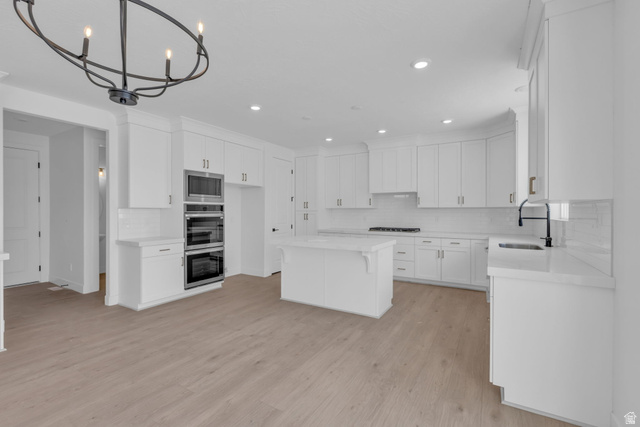 2821 Scarlet Road, Unit 149 Eagle Mountain, UT 84005 - Photo 10 of 28 Bright kitchen featuring full-height white cabinetry, a central island, LED lighting, professional grade appliances including double oven, microwave, dishwasher and gas cooktop.